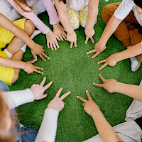 Lapset istuvat ympyrässä lattialla ja näyttävät sormilla eri lukumääriä