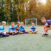 Valmentaja ohjeistaa lapsia jalkapallokentällä