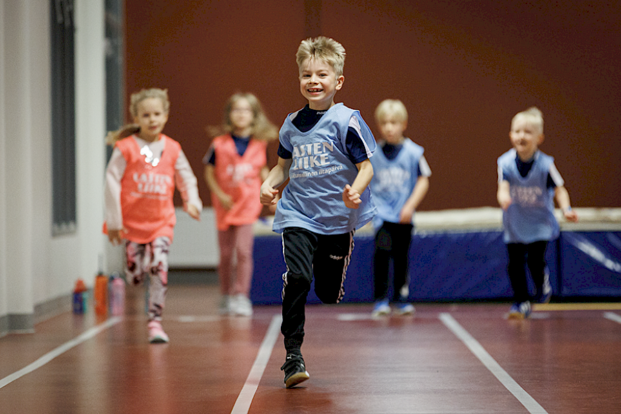 Lapset juoksevat juoksuradalla Lasten Liike -liivit päällään
