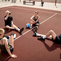 Lentopallon pelaajia istumassa kentällä pelin jälkeen